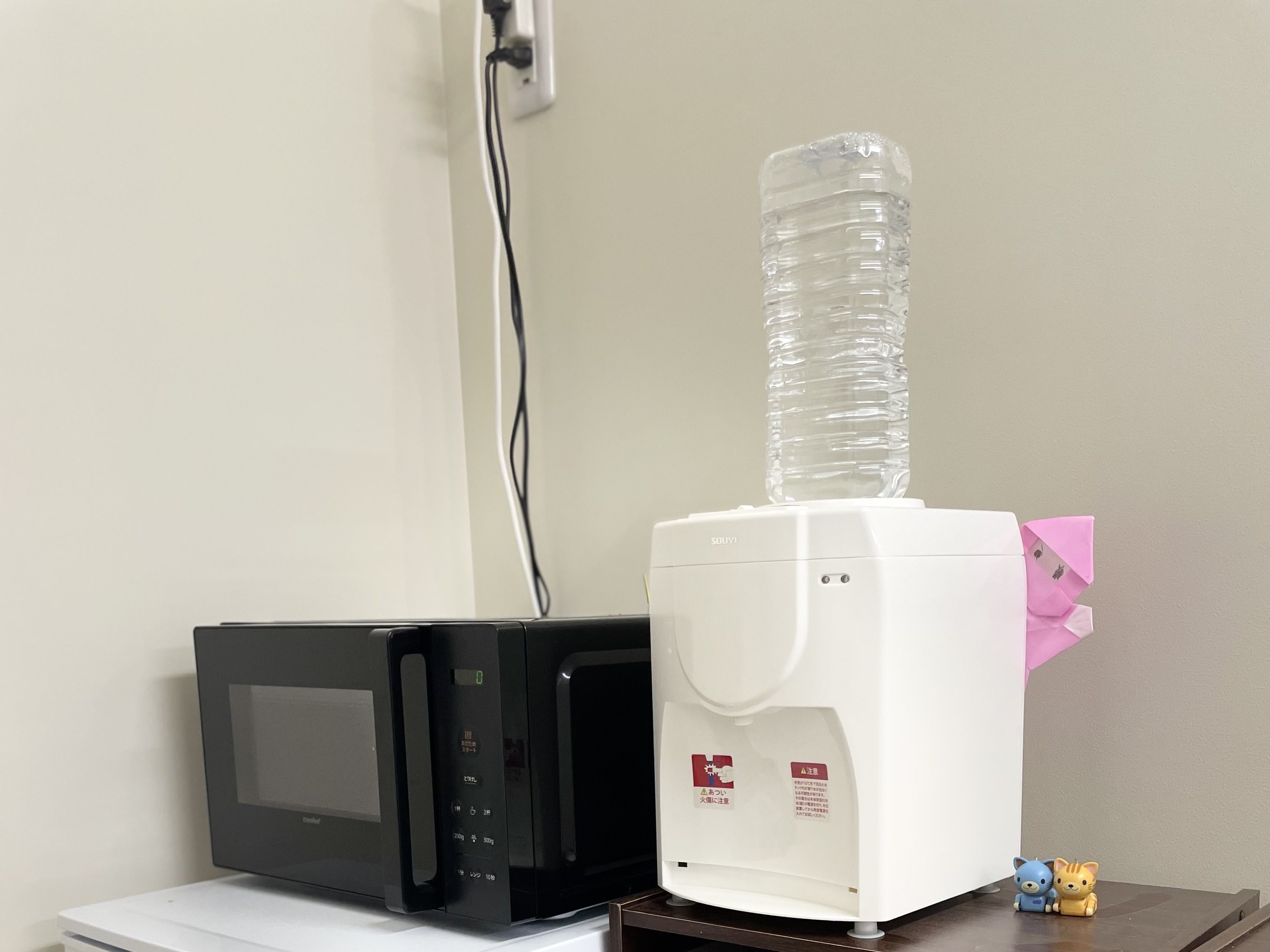 キッチンエリアの一部で、電子レンジと冷蔵庫、水 dispenser が並んでいる画像。